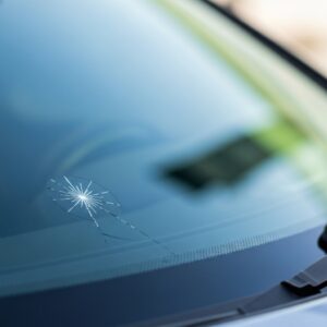 Pare-brise de voiture avec une fissure réparée, symbolisant une aide pour franchise bris de glace et des économies.