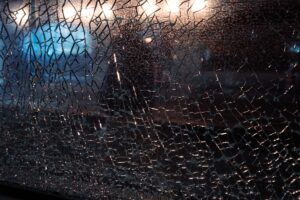Close-up of cracked glass with bokeh lights in background