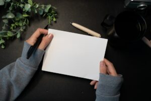 Hands holding blank card with pen and plant