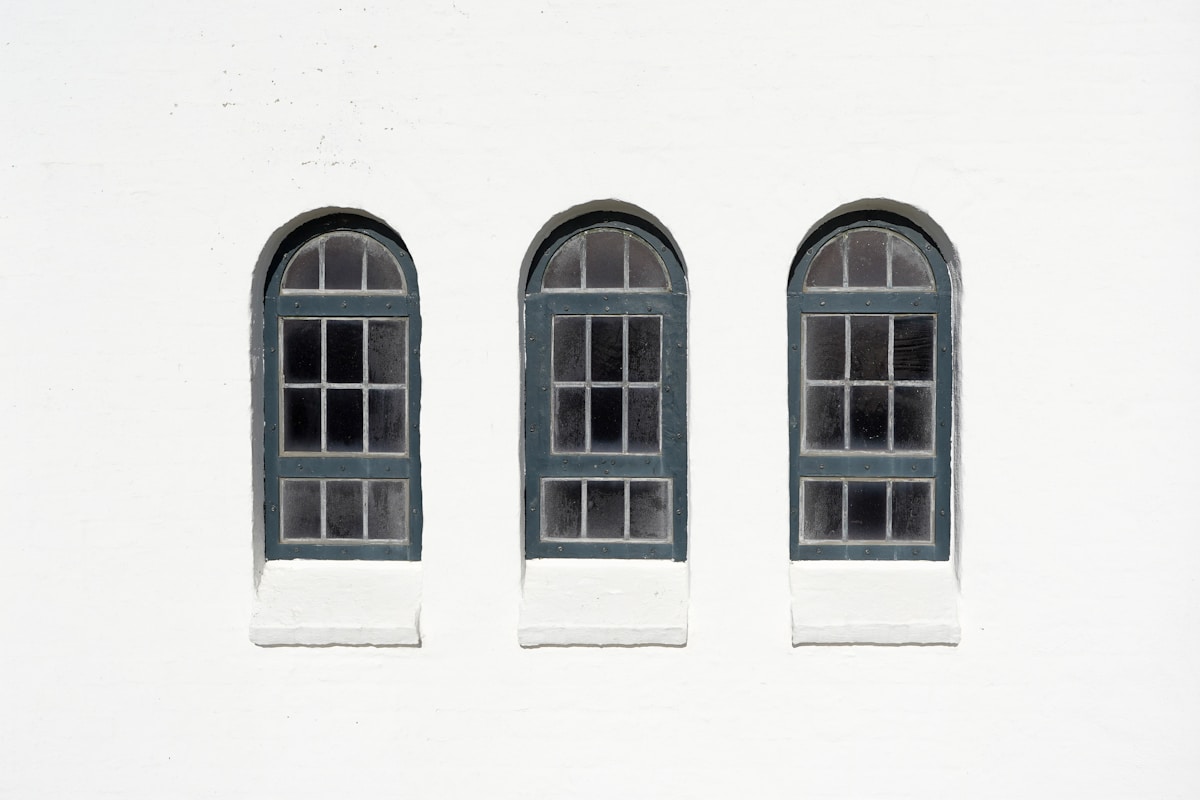 Three arched windows on a white wall