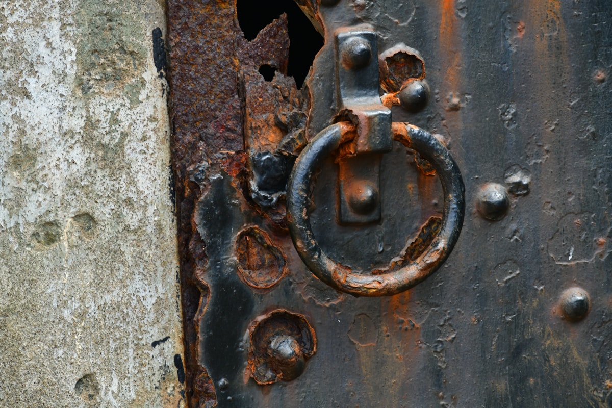 A rusty metal door knocker on a weathered surface