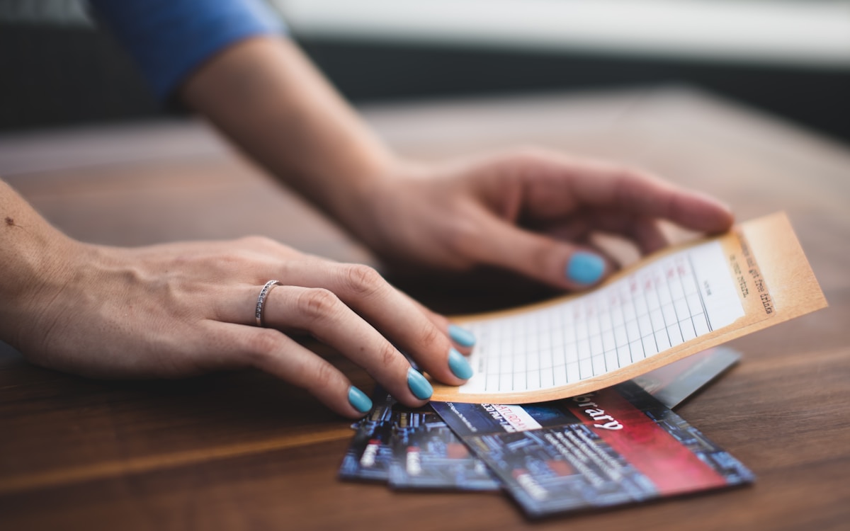 Mains féminines avec vernis bleu, tenant des cartes de crédit et un formulaire.