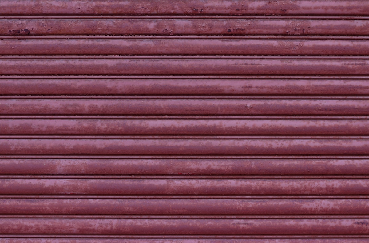 Motifs de lignes horizontales rougeâtres sur une surface texturée.