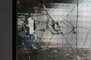 a broken window with a blue fire hydrant behind it