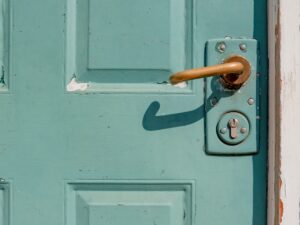 Porte verte vintage avec poignée en bois et serrure rouillée.