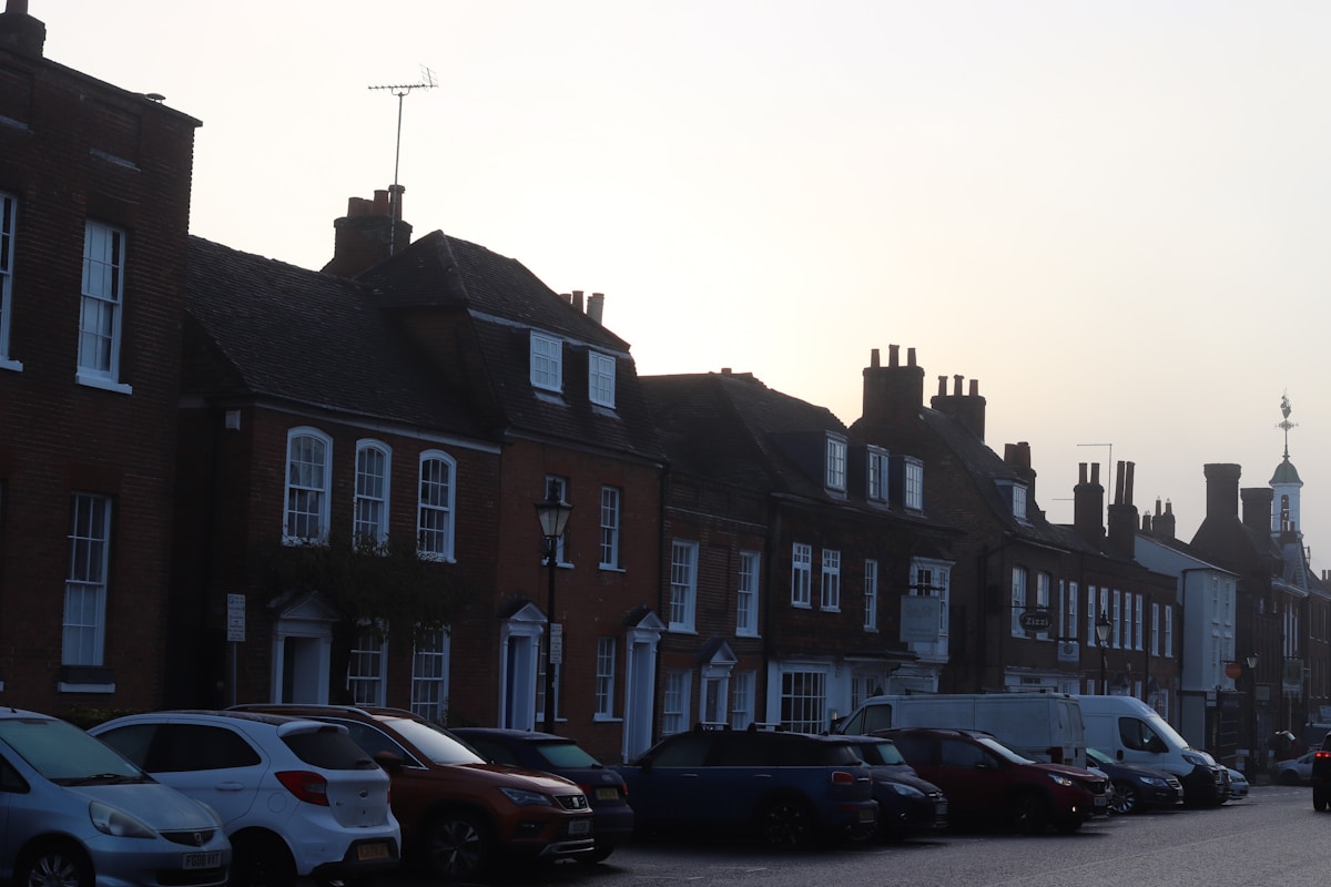 Row of brick houses with parked cars in front.
