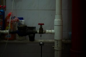 Tuyaux, robinets et bouteilles dans un endroit sombre et encombré.