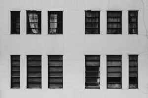 Fenêtres sombres et volets ouverts dans un mur gris.