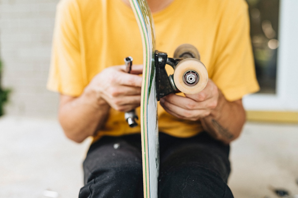 Personne en chemise jaune réparant un skateboard.