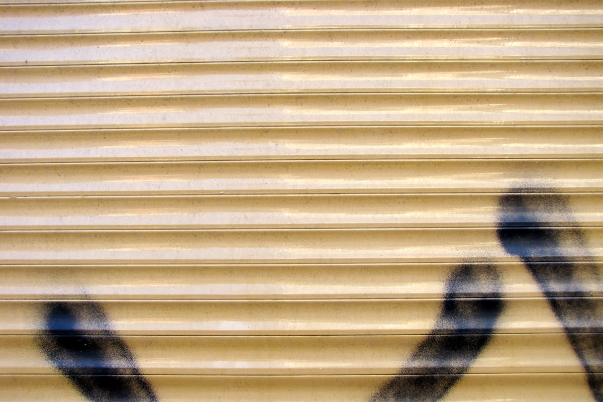 Rideau métallique doré avec des traces de graffiti sombres.