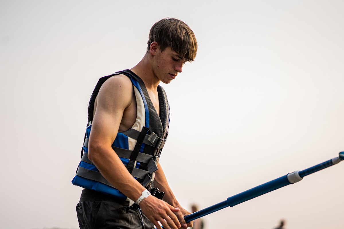 Jeune homme en tenue de sécurité, tenant une barre métallique.