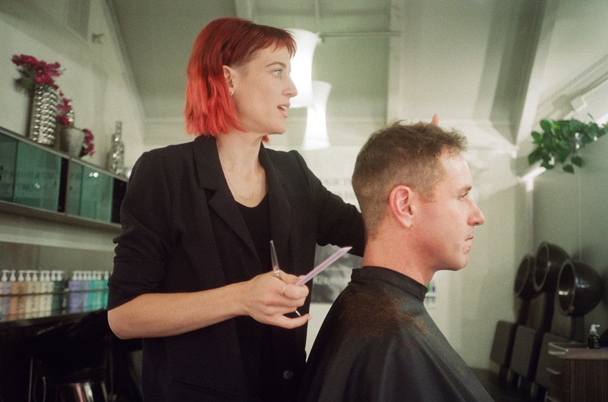 Coiffeur professionnel coupant les cheveux d'un client dans un salon.