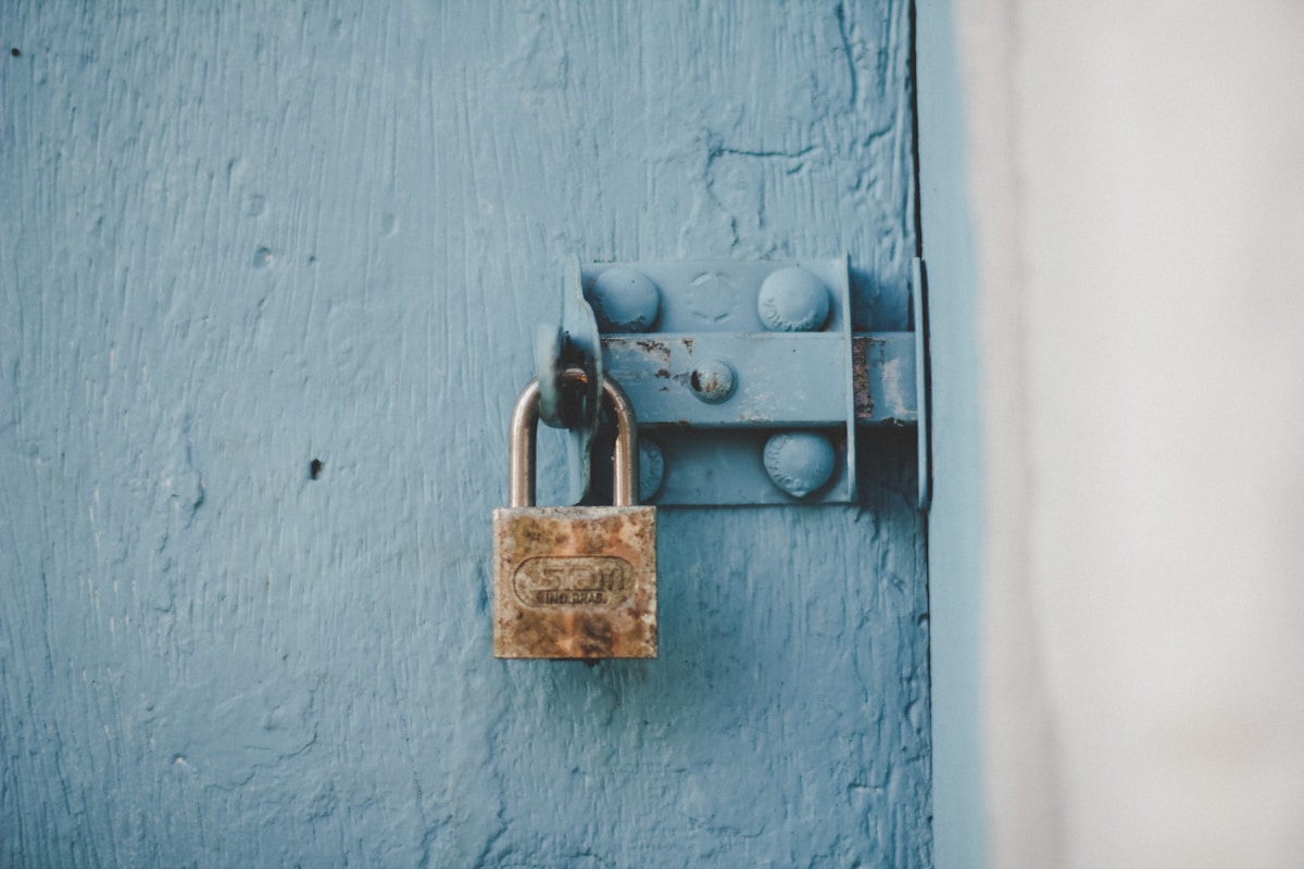 Verrou rouillé sur une porte en bois bleu délavé.