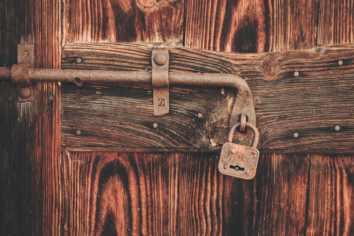 Vieux verrou en métal rouillé sur une porte en bois rustique.