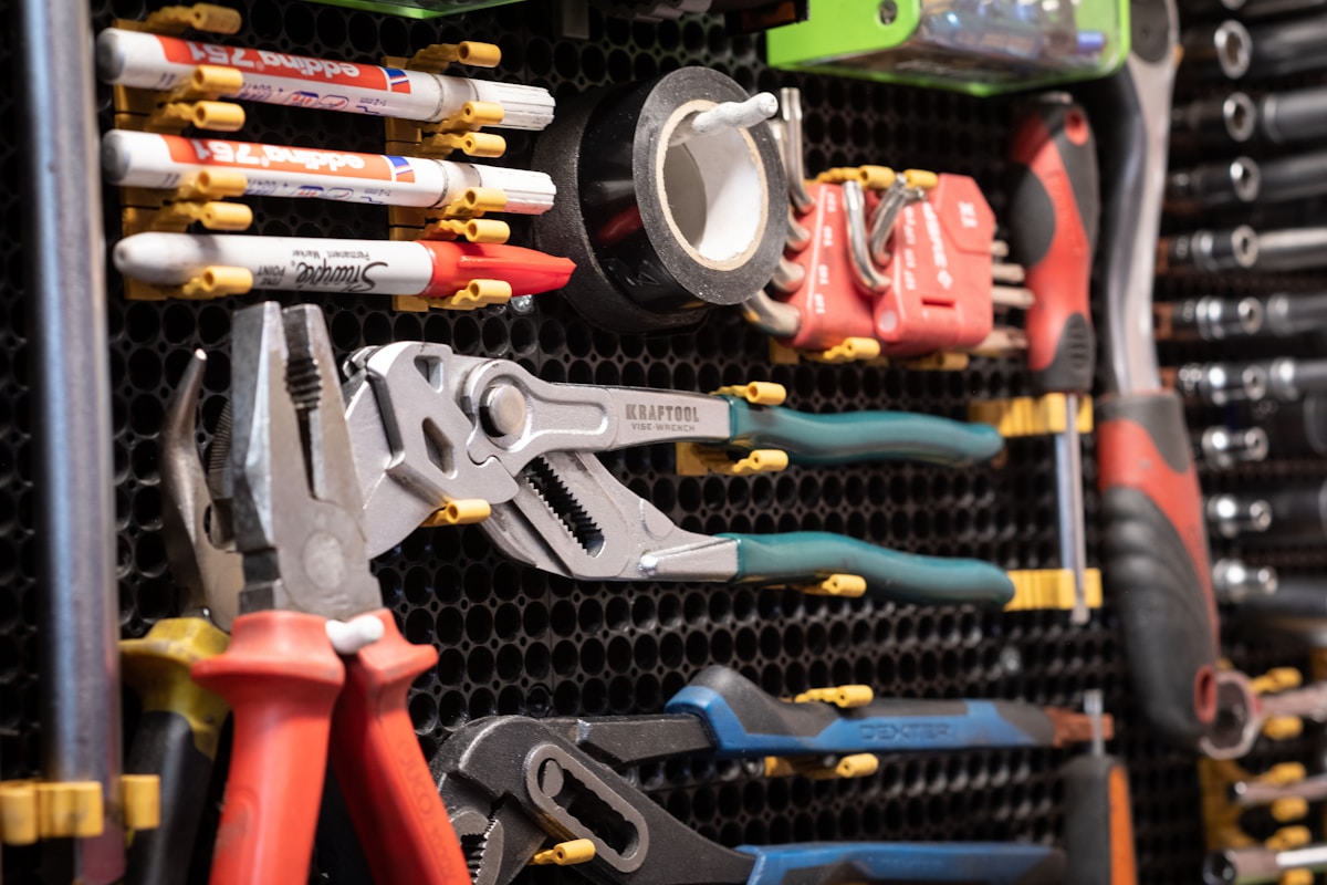 Outils et accessoires de bricolage rangés sur un panneau perforé.