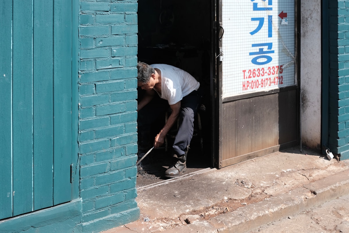 Homme assis dans l'encadrement d'une porte, dans une ruelle.
