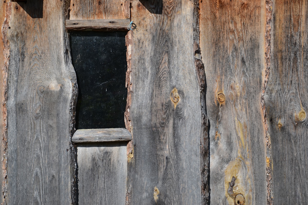Vieille porte en bois rustique avec une ouverture sombre.