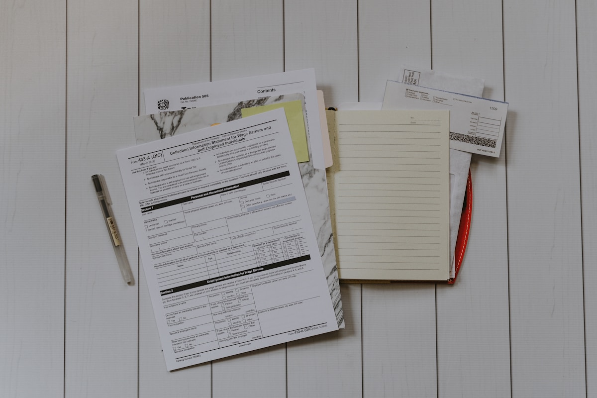 Formulaires, documents, stylo et papier sur un bureau en bois.
