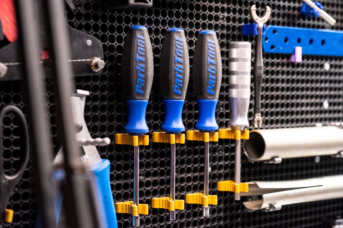 Outils de bricolage bleus et dorés rangés sur un panneau perforé.