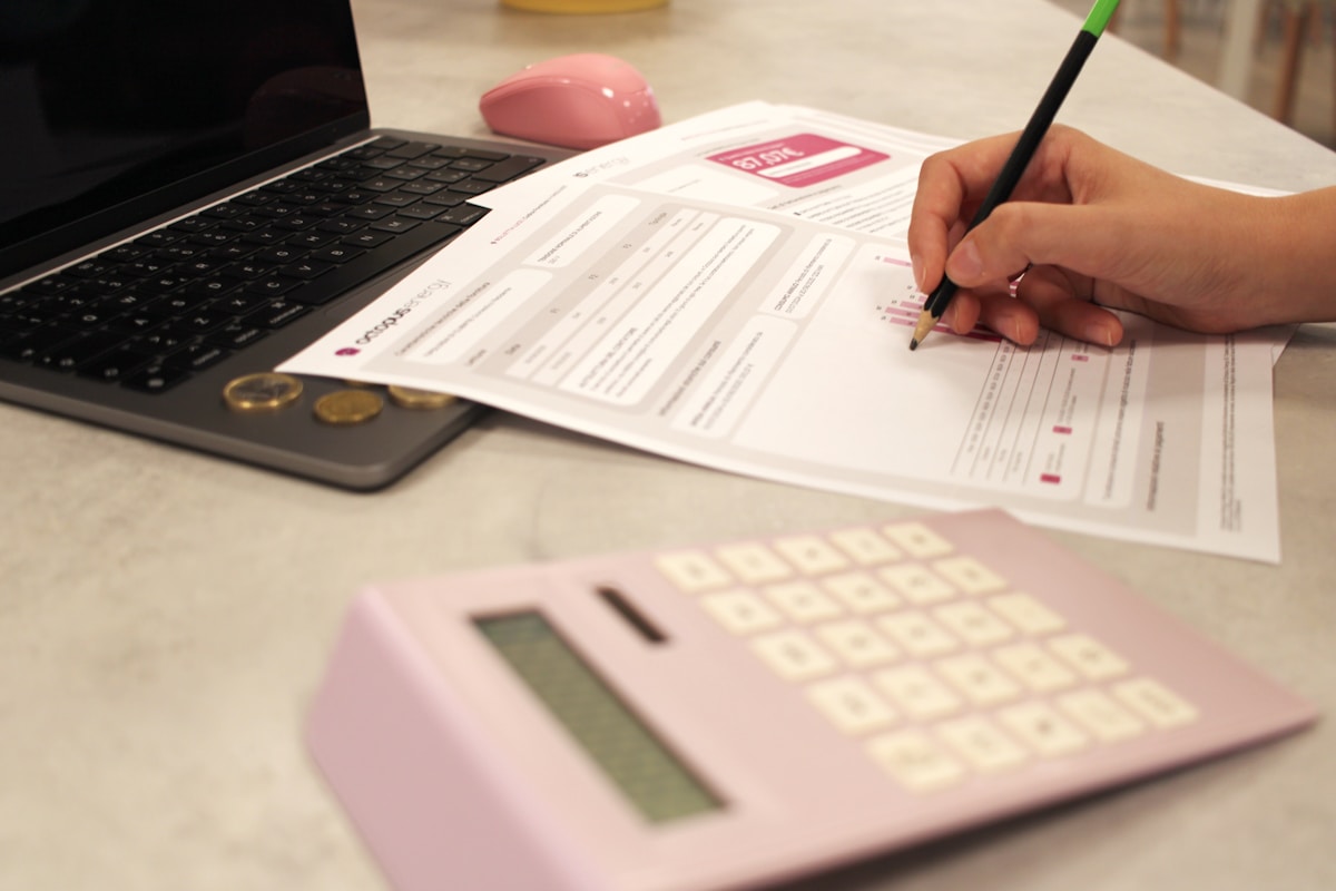 Formulaire de demande rempli à la main avec calculatrice et ordinateur portable.