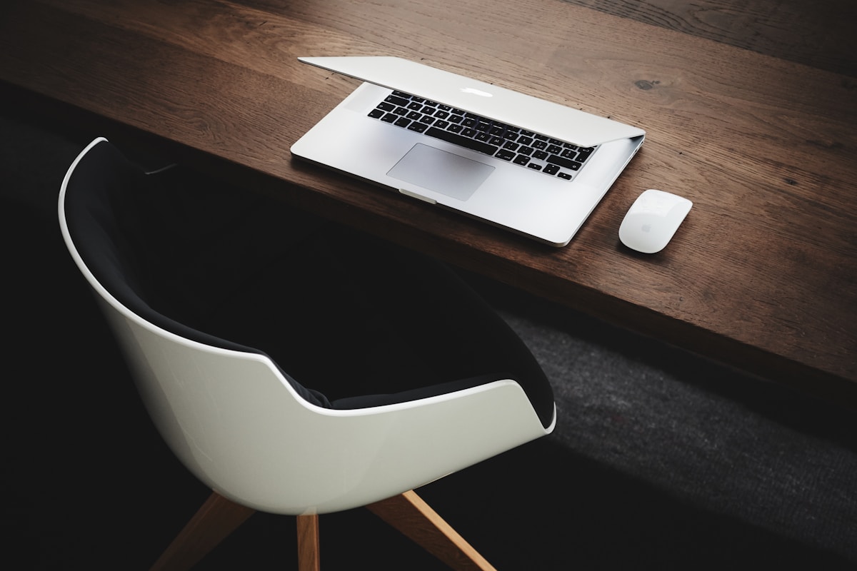 Bureau de travail avec ordinateur portable et souris sur une table en bois.